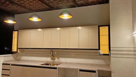 Beige gloss kitchen with lit glass cabinets and pendant lamps
