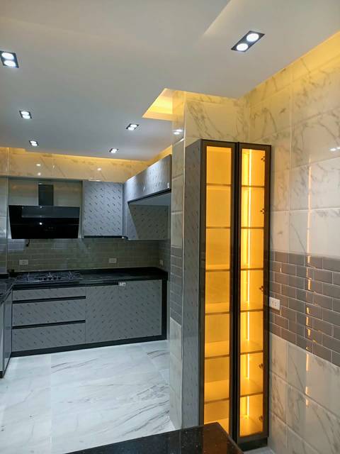Tall lit glass cabinet in a grey kitchen