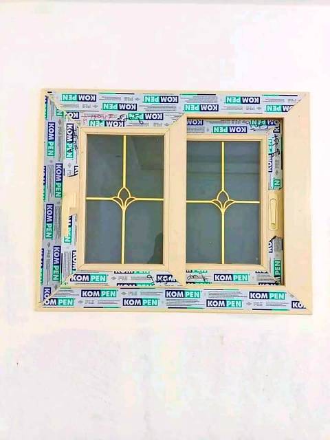 Cream uPVC window with a decorative brass grid